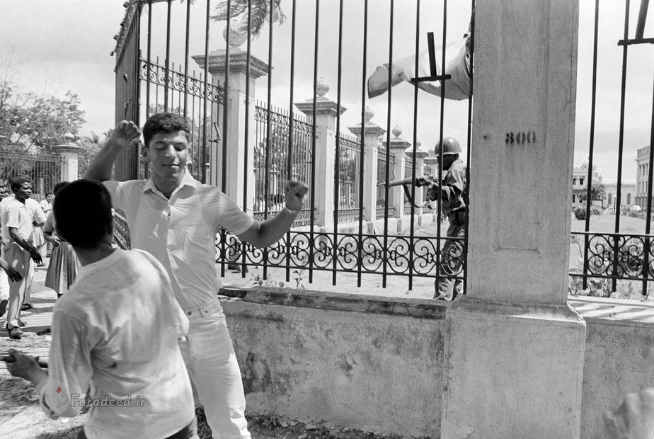 تصویری از یک افسر ارتش دومینیکن در کاخ ملی که در حال شلیک و کشتن دانش آموزان دبیرستانی است. این دانش آموزان به حضور آمریکا در این کشور اعتراض می کردند. در آوریل 1965، ایالات متحده جمهوری دومینیکن را اشغال کرد، و به مت بیش از یک سال از آنجا خارج نشد. این عکس در تاریخ 27 سپتامبر گرفته شده است