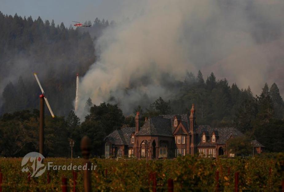 بالگردی در حال ریختن آب بر روی آتش در جریان آتش سوزی های گسترده کالیفرنیا